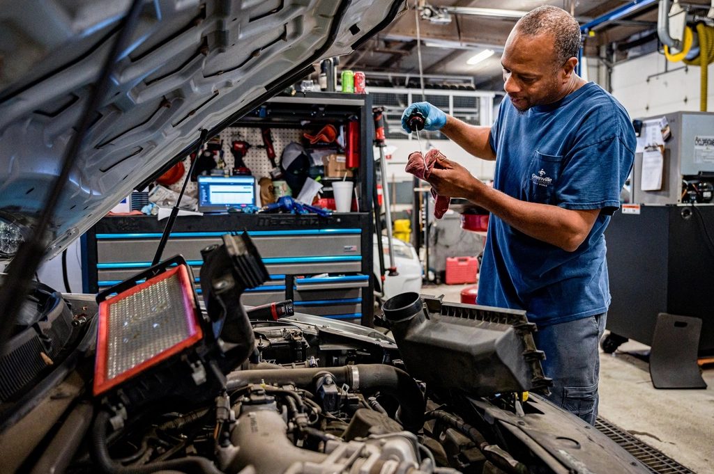 A mechanic checking an engine under an open bonnet
